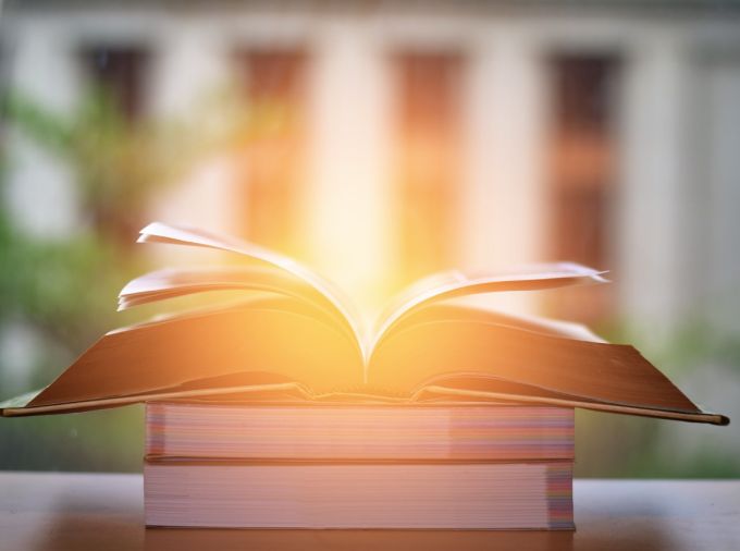 Open Book on wood table and blurred bookshelf in the background